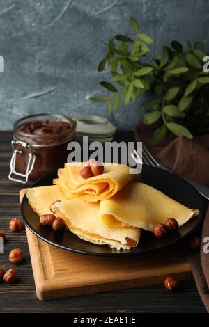 Concetto di colazione con crepes con pasta al cioccolato e noci su tavolo di legno Foto Stock