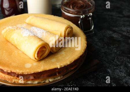 Concetto di colazione con crepes con pasta di cioccolato su nero tavolo per affumicatura Foto Stock