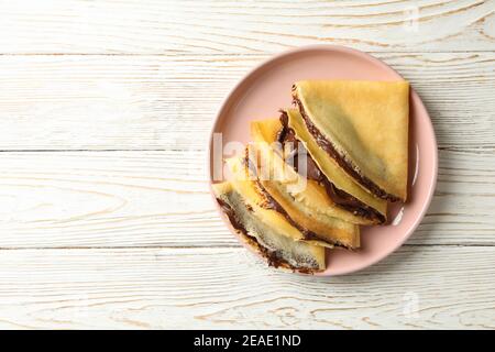 Piatto di crepes con pasta di cioccolato su sfondo bianco di legno Foto Stock