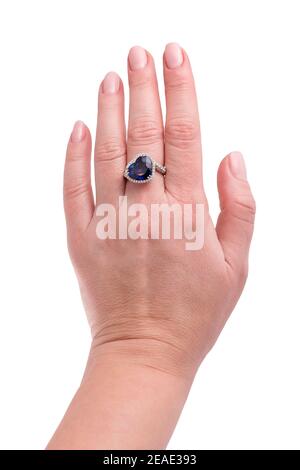 Zaffiro blu a forma di cuore anello prezioso su mano donna isolato su sfondo bianco. Primo piano dell'anello diamantato sulla mano femmina. Anello dorato bianco con Foto Stock