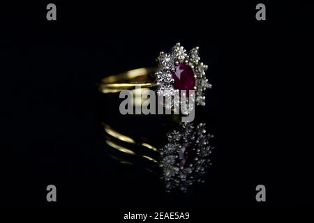 Anello rosso rubino e diamante oro carato 18 una superficie riflessa con sfondo nero Foto Stock