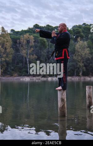 uomo che pratica la disciplina di sipalkido all'aperto in un lago in un giornata di sole con uniforme tradizionale Foto Stock