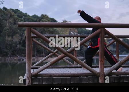 uomo che pratica la disciplina di sipalkido all'aperto in un lago in un giornata di sole con uniforme tradizionale Foto Stock