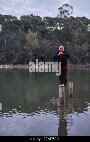 uomo che pratica la disciplina di sipalkido all'aperto in un lago in un giornata di sole con uniforme tradizionale Foto Stock