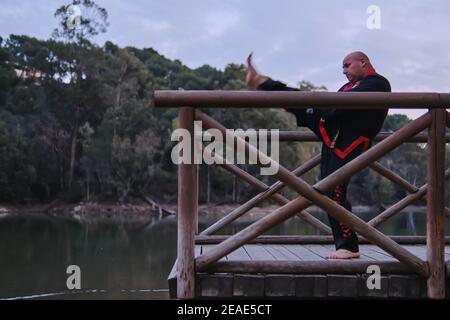 uomo che pratica la disciplina di sipalkido all'aperto in un lago in un giornata di sole con uniforme tradizionale Foto Stock