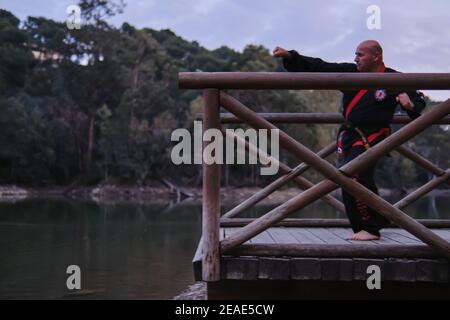 uomo che pratica la disciplina di sipalkido all'aperto in un lago in un giornata di sole con uniforme tradizionale Foto Stock