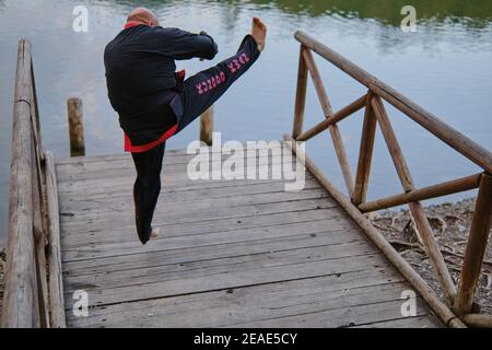 uomo che pratica la disciplina di sipalkido all'aperto in un lago in un giornata di sole con uniforme tradizionale Foto Stock