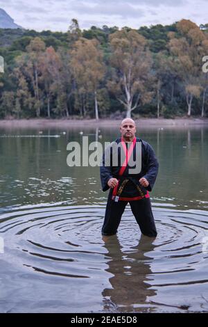 uomo che pratica la disciplina di sipalkido all'aperto in un lago in un giornata di sole con uniforme tradizionale Foto Stock