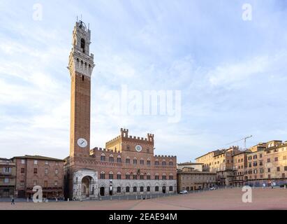 Torre del Mangia, una torre rinascimentale e palazzo sono illuminati dalla luce dell'alba in piazza del campo a Siena, famosa per la corsa di cavalli di strada del Palio, a Tus Foto Stock