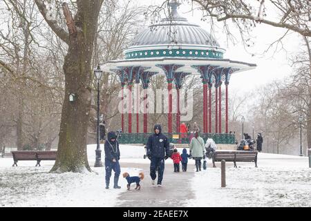 Londra, Regno Unito. 9 febbraio 2021: Dopo tre giorni di neve a Londra inizia a stabilirsi e i venti sono caduti mentre Storm Darcy è passato. Su Clapham Common alcune persone prendono l'esercizio vicino al supporto band con i loro bambini o cani. Anna Watson/Alamy Live News Foto Stock