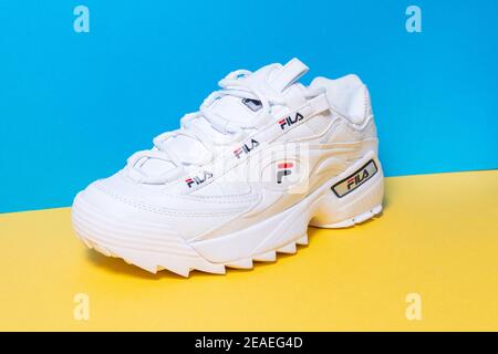 Tyumen, Russia-27 novembre 2020: Sneakers donna fila bianco su uno sfondo multicolore blu giallo. Foto Stock