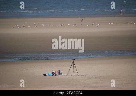 Un fotografo si trova da solo sulla spiaggia di Rhyl in Galles aspettando Per l'avvio di Airshow Foto Stock