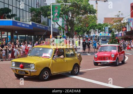 Mini auto classiche che prendono parte a una parata di Natale a Tauranga, Nuova Zelanda, decorate con regali e un albero di Natale Foto Stock