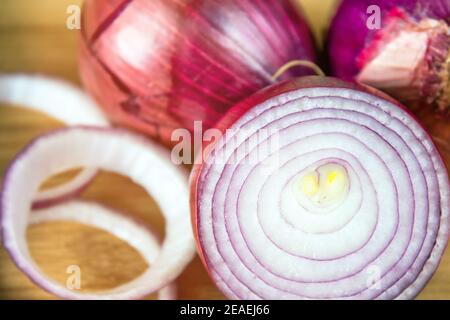 Cipolle rosse, approccio realistico agli ingredienti alimentari, primo piano di tre grandi cipolle rosse su una superficie di legno. Foto Stock