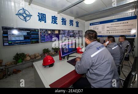(210209) -- ZHONGNING, 9 febbraio 2021 (Xinhua) -- gli ufficiali responsabili di un progetto di tunnel attraverso il Fiume giallo danno le indicazioni all'interno della sala di comando nella Contea di Zhongwei, città di Ningxia Hui Autonomous Reigon, 9 febbraio 2021. Oltre 100 lavoratori sono ancora in servizio nel tunnel per garantire lo sviluppo del progetto in tempo nonostante il prossimo Spring Festival, o il cinese Lunar New Year. Questo tunnel, il secondo ad attraversare il Fiume giallo in Ningxia, fa parte di un progetto più grande per fornire il servizio di riscaldamento ai residenti in Zhongning. (Xinhua/Feng Kaihua) Foto Stock