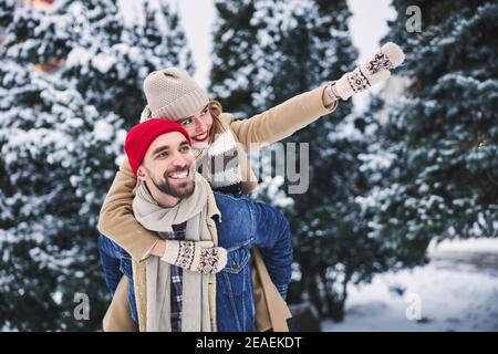 Felice ragazza che cavalca il ragazzo nella foresta innevata Foto Stock