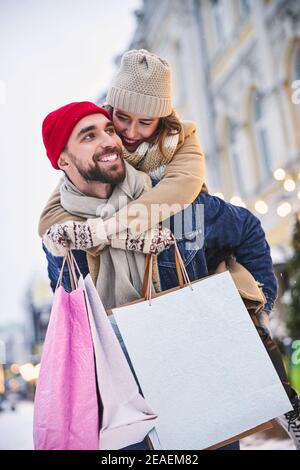 Donna allegra che guida il ragazzo in città d'inverno Foto Stock