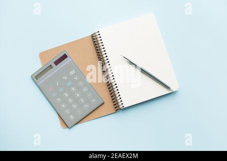 Notebook in carta con calcolatrice e penna su sfondo blu. Concetto di alimentazione sana - calcola l'assunzione di alimentazione quotidiana. Vista dall'alto. Foto Stock