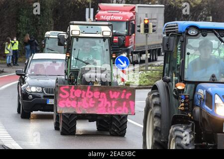 Friedrichshafen, Germania. 09 febbraio 2021. Con l'iscrizione 'se moriamo, anche tu muori' sulla parte anteriore del trattore, un agricoltore dimostra nei dintorni dell'ufficio amministrativo distrettuale nel distretto del lago di Costanza contro la legge prevista per la protezione degli insetti. Circa 150 agricoltori con i loro trattori fanno il giro intorno all'ufficio amministrativo del distretto. Credit: Felix Kästle/dpa/Alamy Live News Foto Stock