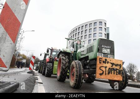 Friedrichshafen, Germania. 09 febbraio 2021. Con l'iscrizione 'Salto esproprio!' Sulla parte anteriore del trattore, un agricoltore dimostra nei dintorni dell'ufficio amministrativo distrettuale del distretto di Lake Constance contro la legge prevista per la protezione degli insetti. Circa 150 agricoltori con i loro trattori fanno il loro giro intorno all'ufficio distrettuale. Credit: Felix Kästle/dpa/Alamy Live News Foto Stock