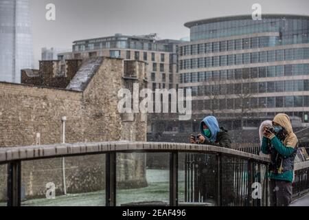 Londra, Regno Unito. 9 Feb 2021. I turisti scattano fotografie del fossato innevato che circonda la Torre di Londra, attualmente ricoperta di neve, quando le temperature di congelamento colpiscono Londra durante la tempesta Darcy. Londra, Inghilterra. 9 Febbraio 2021 Credit: Jeff Gilbert/Alamy Live News Foto Stock