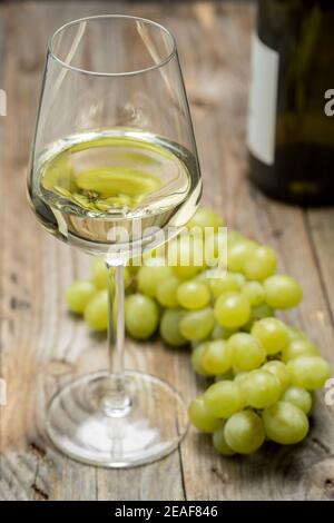 Bicchiere di vino con uva su sfondo ligneo. Foto Stock