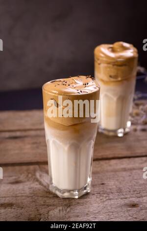 Caffè Dalgona. Bevanda ghiacciata montata con caffè istantaneo popolare in Corea cocktail cremoso in bicchieri alti. Fotografia di cibo con moody scuro Foto Stock