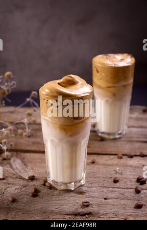 Caffè Dalgona. Bevanda ghiacciata montata con caffè istantaneo popolare in Corea cocktail cremoso in bicchieri alti. Fotografia di cibo con moody scuro Foto Stock