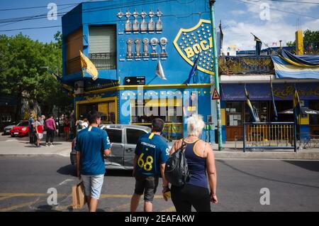 Buenos Aires, Argentina - Gennaio, 2020: Tifosi di calcio del Boca Juniors club attraversando la strada vicino allo stadio la Bombonera e negozio di fan di fronte ad esso Foto Stock