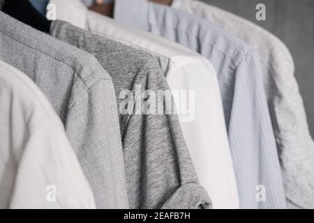Camicie e t-shirt in cotone appese nell'armadio. Semplice casual unisex stile, simili opzioni di vestizione, tessile, moda Foto Stock