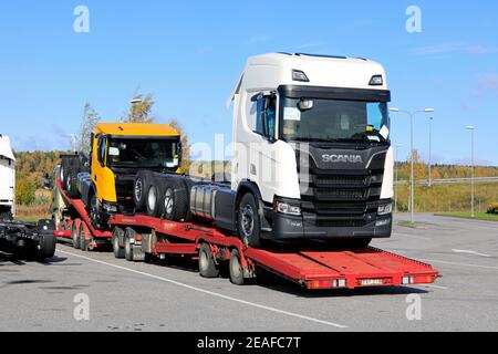 Supporto per veicoli che trasporta due nuovi carrelli Scania, bianco R650 e giallo R650 XT, parcheggiato nel deposito di sosta per camion. Salo, Finlandia. 5 ottobre 2019. Foto Stock