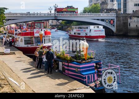 Attrazioni turistiche di York sul panoramico fiume Ouse (passeggeri a bordo e barca a vela su navi da crociera, tour bus, gelateria) - Nord Yorkshire, Inghilterra Regno Unito. Foto Stock