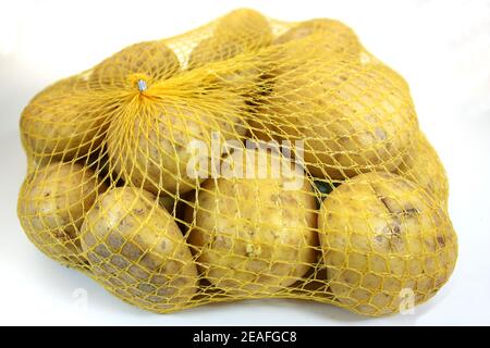 Colpo di chioccia di patate appena raccolte in una rete gialla isolato su sfondo bianco Foto Stock