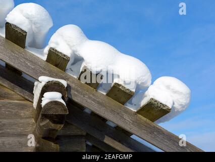 Neve deriva sul tetto dopo di nevicate in giornata di sole. Vecchia casa di legno nella neve. Foto Stock