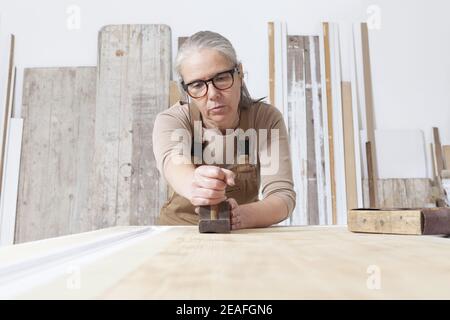 artigianato del legno, falegname artigianale donna lavora legno con vecchio utensile pialla maniglia nel suo laboratorio, restauro, fai da te e lavori fatti a mano concetto Foto Stock