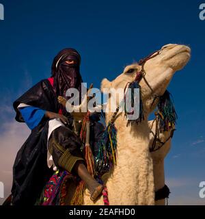 Tuareg uomo che cavalca il suo cammello, Tripolitania, Ghadames, Libia Foto Stock