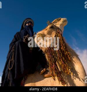 Tuareg uomo che cavalca il suo cammello, Tripolitania, Ghadames, Libia Foto Stock