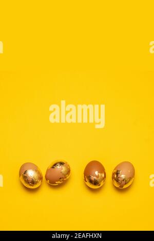 Uova dorate di Pasqua su sfondo giallo con spazio di copia. Disposizione piatta Foto Stock