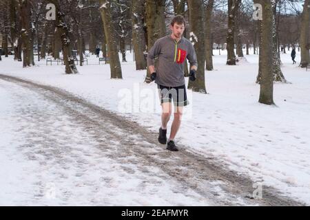 Un uomo che corre nel centro di Edimburgo dopo un'inizio mattina nevicata Foto Stock