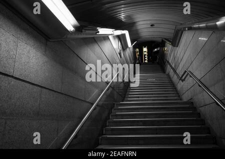 Prospettiva sottopasso oscuro vuoto. Le scale di pietra saliscono sotto le luci bianche al neon. Astratto notte città sfondo Foto Stock