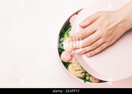 Primo piano le mani di donne che aprono le scatole di regalo con i fiori freschi. Arriva la primavera, giornata internazionale delle donne, giornata felice delle valentine, 8 marzo, giornata delle madri Foto Stock