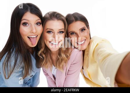 Tre donne in tute pastello che posano su sfondo bianco Foto Stock