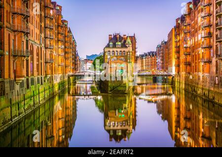 Vista notturna del famoso castello d'acqua nel quartiere dei magazzini Speicherstadt ad Amburgo, Germania. Foto Stock