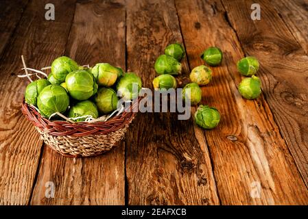 brussel crudo germogli in un cestino su un vecchio legno tabella Foto Stock