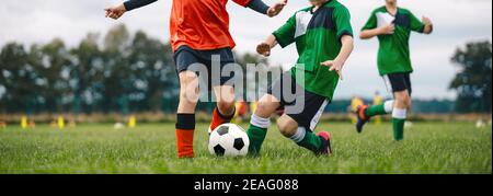 I giocatori calciano la palla da calcio sull'erba. Ragazzi in un duello di calcio. Gruppo di bambini della scuola che giocano a sport all'aperto sul campo da calcio. I bambini competono dentro Foto Stock