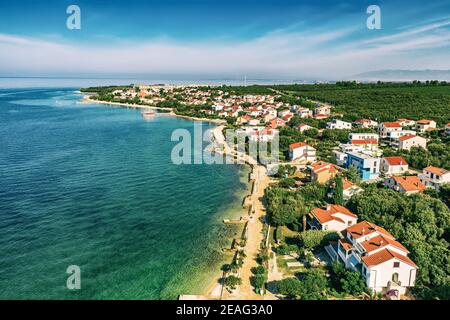 Veduta aerea dall'alto del villaggio Petrcane, Croazia. Sfondo turistico con mare blu, costa e tetti rossi. Riviera di Zara, Dalmacia Foto Stock