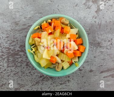 Vista dall'alto della frittura di verdure miste con verdure e germogli di fagioli in una ciotola su sfondo grigio. Foto Stock