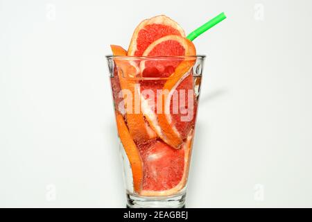 Il pompelmo affettato in un bicchiere con acqua gassata e cocktail tubetto rosso. Foto Stock