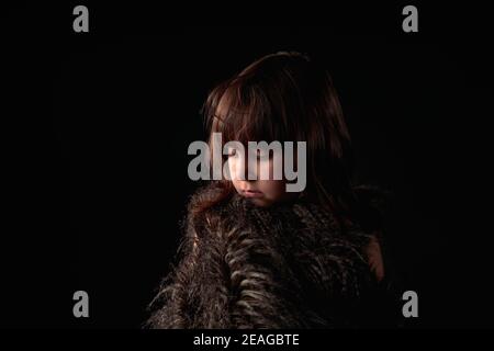 Elegante ragazza caucasica di quattro anni vestita con gilet in piuma con espressione adorabile e endearing Foto Stock