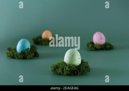 Uova colorate di Pasqua adagiato sul cuscino di muschio su sfondo verde. Buona Pasqua. Colori disattivati. Messa a fuoco selettiva. Spazio di copia Foto Stock